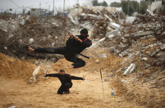 Hai thanh niên Palestine trình diễn võ thuật theo phong cách ninja trước những ngôi nhà đổ nát ở Dải Gaza.