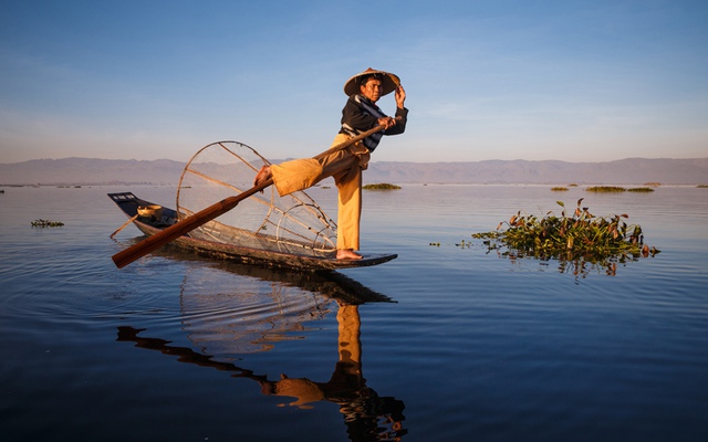 Ngư dân dùng chân chèo thuyền trong khi đánh cá trên hồ Inle ở Myanmar.