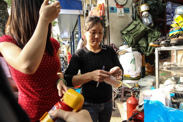 
Một người phụ nữ bóc tem để dán vào các bình chữa cháy, các loại tem này khá sơ sài và không ghi rõ hạn sử dụng của sản phẩm - Ảnh Nguyễn Khánh
