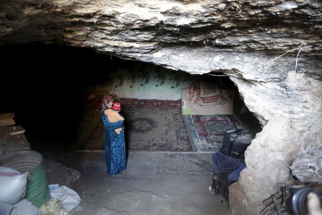 Người phụ nữ bế con bên trong hang động dưới chân núi.