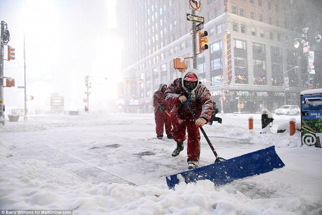 
Các công nhân vất vả dọn tuyết trên đường ở New York.
