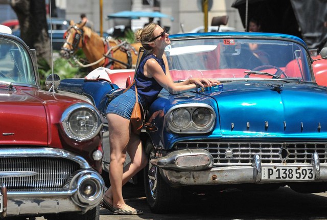 Du khách chụp ảnh với ô tô cổ do Mỹ sản xuất tại thành phố Havana, Cuba.