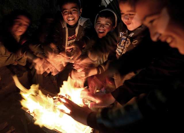 Các cậu bé người Palestine sưởi ấm quanh một đống lửa khi điện bị cắt tại trại tị nạn Al Shateaa ở thành phố Gaza.