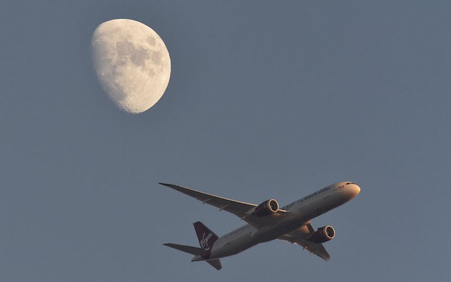 Máy bay chở khách lướt qua mặt trăng trên bầu trời thành phố London, Anh.