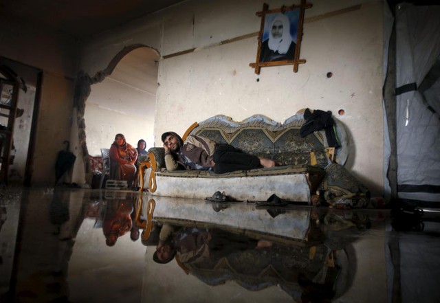 Người đàn ông Palestine nằm trên ghế trong ngôi nhà bị ngập lụt tại thị trấn Beit Hanoun, Dải Gaza.