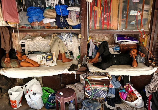 Công nhân ngủ trong giờ nghỉ trưa tại một cửa hàng giặt là ven đường ở thành phố Mumbai, Ấn Độ.