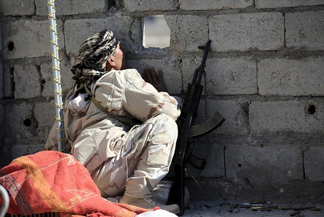 
Binh sĩ quân đội chính phủ quan sát qua một lỗ nhỏ trên tường tại thành phố Falluja, Iraq.
