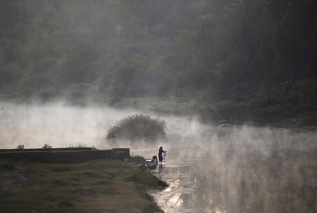 Người phụ nữ giặt quần áo lúc sáng sớm trên sông Kaveri ở Kushalnagar, Indonesia.