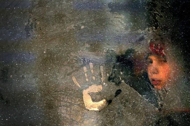 
Cậu bé nhìn qua khung cửa sổ bị đóng băng của một chiếc xe bus ở Minsk, Belarus.
