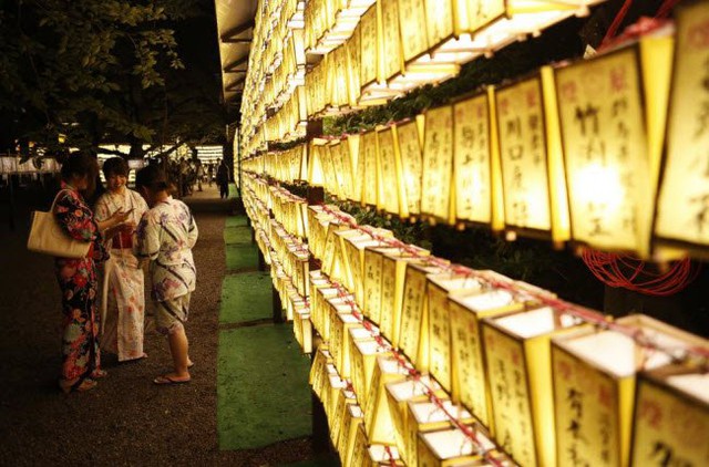 
Những người phụ nữ mặc kimono truyền thống xem bức ảnh họ chụp trước đèn lồng giấy trong lễ hội Mitama tại ngôi đền Yasukuni ở Tokyo.
