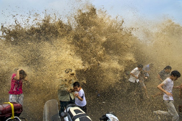 
Khách du lịch tìm cách thoát khỏi cơn bão thủy triều tràn qua đê biển của bờ sông Tiền Đường, tỉnh Chiết Giang, Hàng Châu, Trung Quốc vào ngày 25 Tháng Tám 2013.

