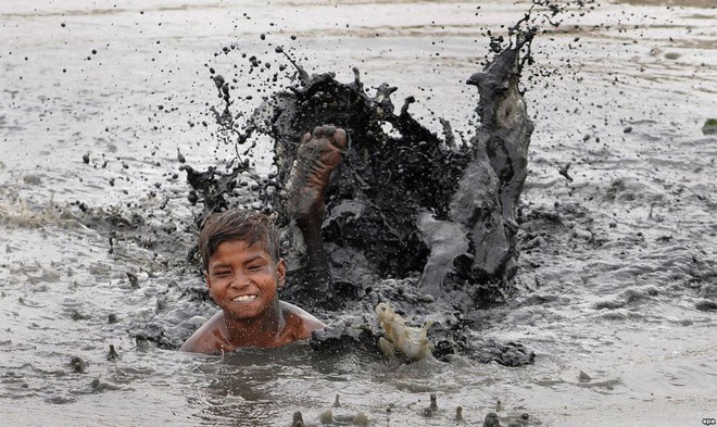 Cậu bé thích thú bơi dưới nước bùn trong một ngày nắng nóng ở thành phố New Delhi, Ấn Độ.