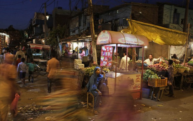 Người bán kem dạo ngồi chờ khách hàng tại một khu chợ ở New Delhi, Ấn Độ.