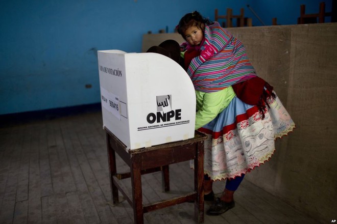 
Người phụ nữ cõng con trên lưng trong khi bỏ phiếu trong cuộc tổng tuyển cử ở Iquicha, Peru.
