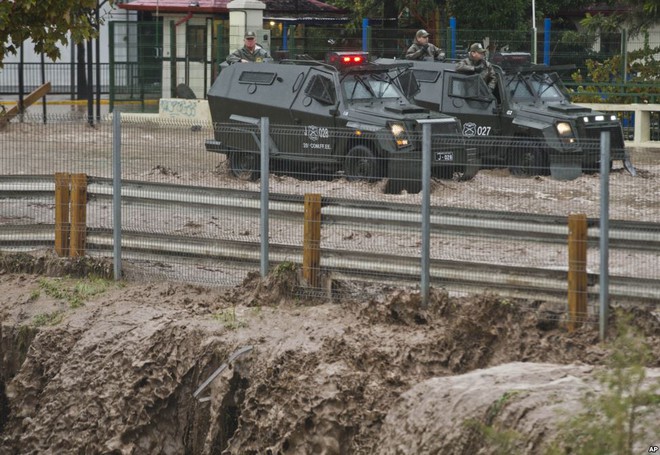 Hai phương tiện bọc thép của cảnh sát đi qua đường ngập lụt sau mưa lớn tại thành phố Santiago, Chile.