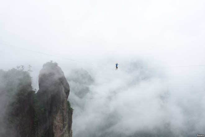 Người đàn ông biểu diễn đi trên dây nối giữa hai đỉnh núi tại thành phố Thái Châu, tỉnh Chiết Giang, Trung Quốc.