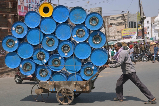 Một người lao động đẩy chiếc xe đầy thùng phi dọc theo con đường ở Amritsar, Ấn Độ.