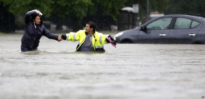 
Người đàn ông nắm tay vợ đi qua đường phố ngập lụt dưới trời mưa ở thành phố Houston, bang Texas, Mỹ.
