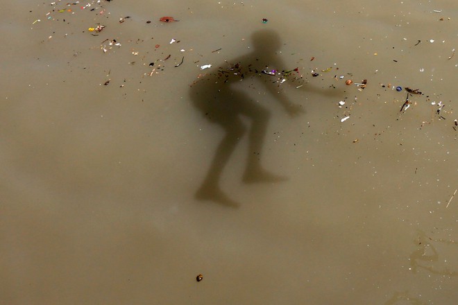 Bóng của một cậu bé nhảy xuống dòng nước ô nhiễm dưới sông Hằng ở ngoại ô thành phố Kolkata, Ấn Độ.