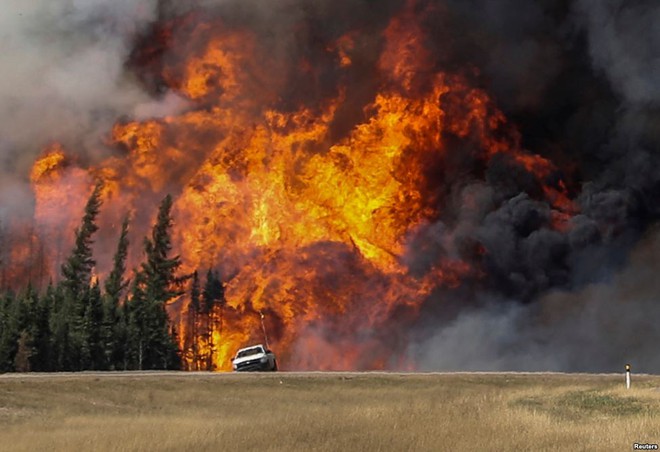Khói và cháy rừng dữ dội ngay phía sau một chiếc ô tô trên đường ở Fort McMurray, Alberta, Canada.