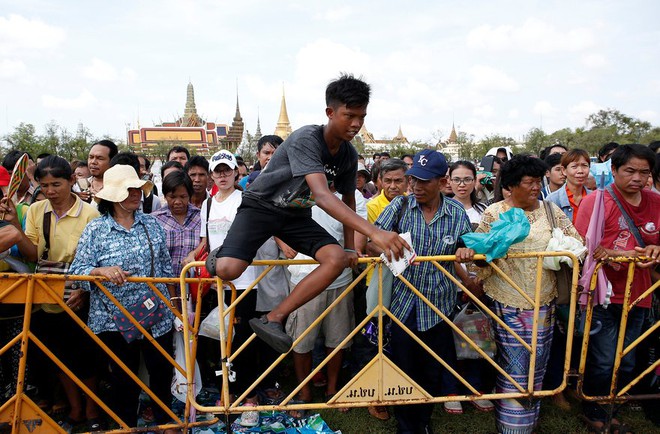 Cậu bé nhảy quả rào chắn để lượm thóc tại một nghi lễ xuống đồng được tổ chức hàng năm ở Bangkok, Thái Lan.