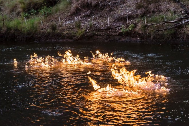 Lửa bốc cháy trên mặt nước do khí gas phun lên từ dưới đáy sông Condamine ở Australia.