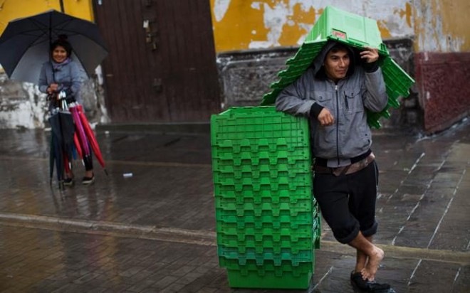 Người đàn ông đứng dưới trời mưa ở thành phố Ayacucho, Peru.