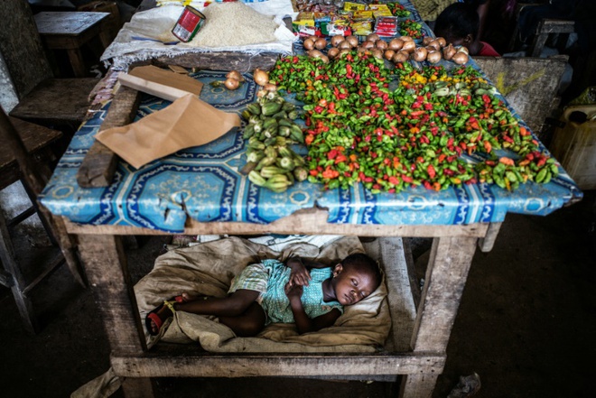 Em bé ngủ ngon lành ngay bên dưới sạp bán hàng tại khu chợ Jorkpan ở thành phố Monrovia, Liberia.