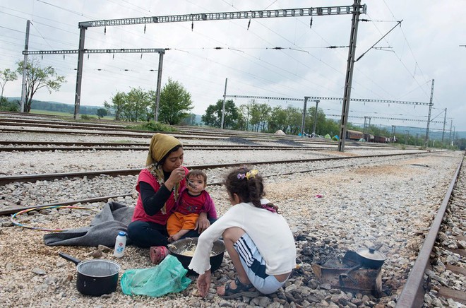 Người phụ nữ di cư chăm sóc cho đứa con nhỏ bên đường ray tàu hỏa gần trại tị nạn ở thị trấn Idomeni, Hy Lạp.