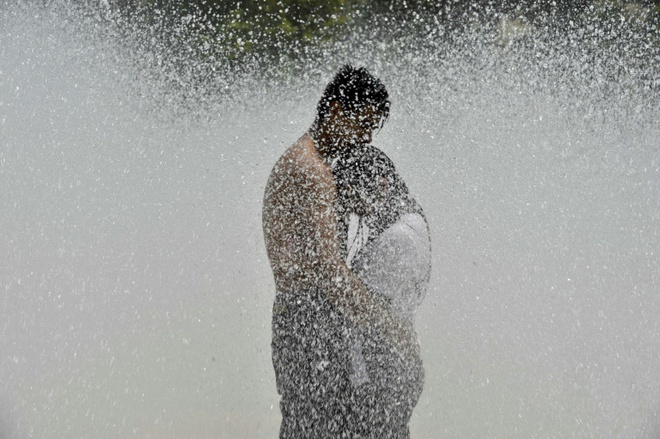 Cặp tình nhân đứng tránh nóng tại đài phun nước ở quảng trường Cách mạng, thành phố Mexico City, Mexico.