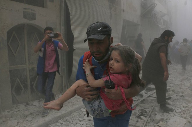 
Người đàn ông bế bé gái bị thương tại hiện trường vụ không kích nhằm vào thành phố Aleppo, Syria.
