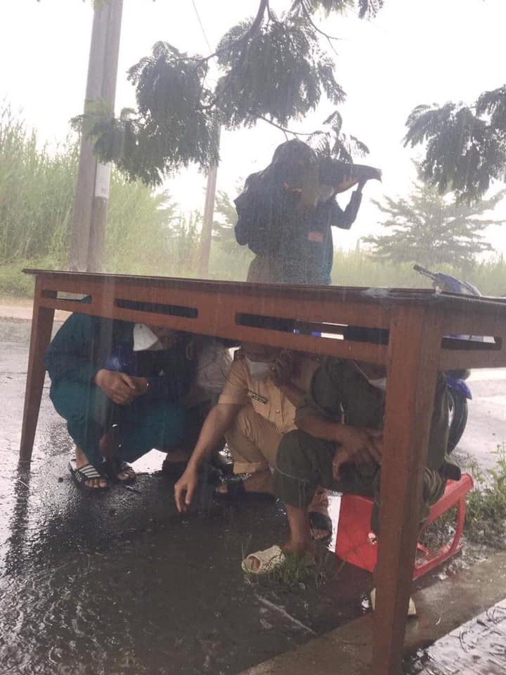 CSGT và đội trực chốt kiểm dịch nép dưới gầm bàn trú mưa, nhìn xuống đôi dép lại càng thêm xót xa - Ảnh 1. CSGT và đội trực chốt kiểm dịch nép dưới gầm bàn trú mưa, nhìn xuống đôi dép lại càng thêm xót xa - Ảnh 1.