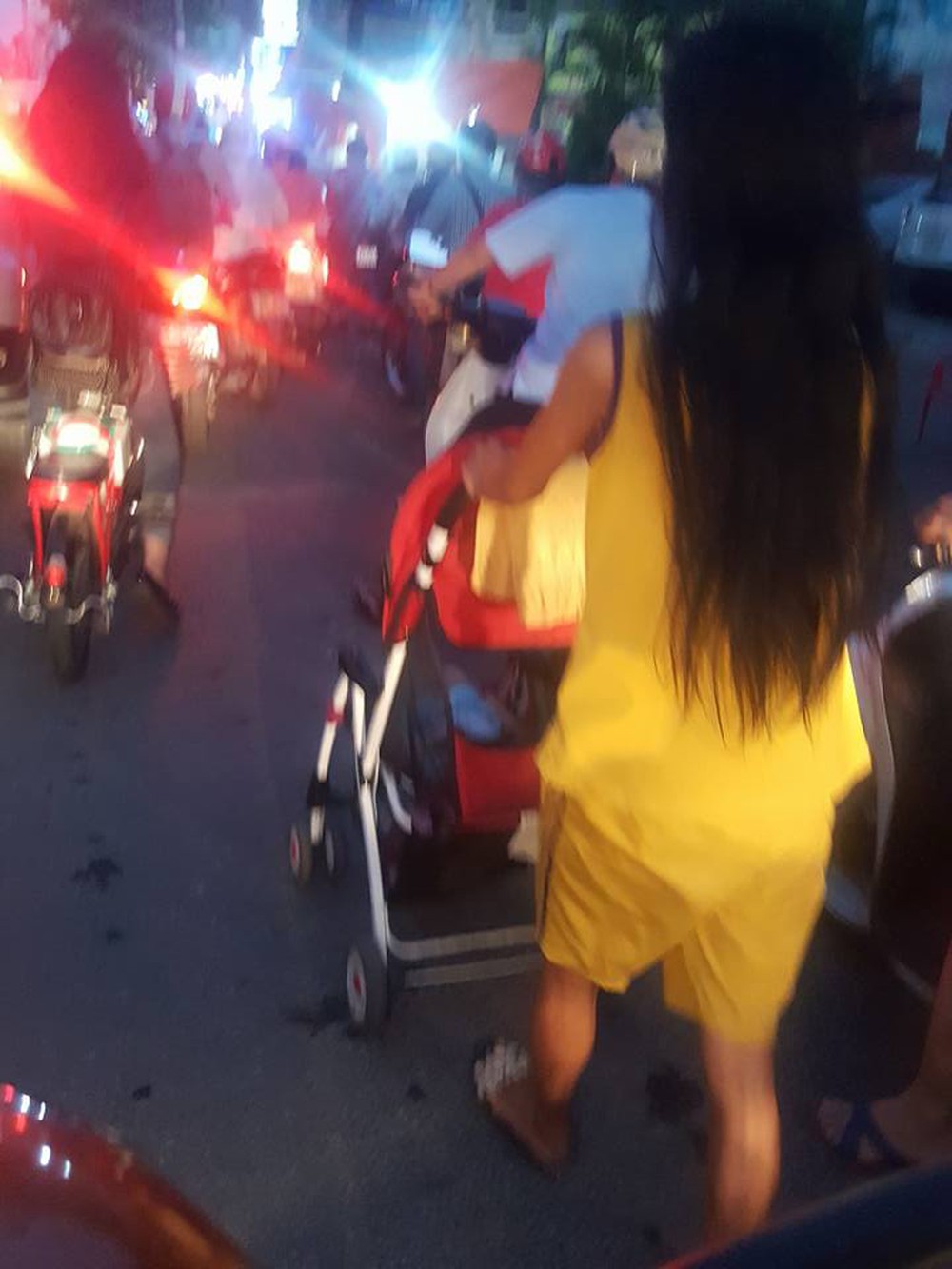 Người phụ nữ đẩy xe nôi em bé giữa phố tắc đường đầy khói xe - Ảnh 1.