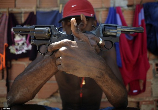 Một người buôn bán ma túy có tên là Pilintra chụp ảnh với 2 khẩu súng ngắn tại khu ổ chuột ở thành phố Salvador.