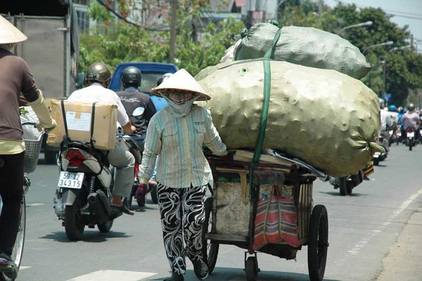 Chị Nguyễn Thị Thủy, 45 tuổi, quê Hoằng Hóa, Thanh Hóa, đang ì ạch đẩy chiếc xe đồng nát đi dọc quanh khu vực bến xe miền Đông. Chị Thủy cho biết, mỗi ngày chị đi thu mua, nhặt ve chai quanh khu vực bến xe. “Dọc bến xe có nhiều trạm xe buýt. Người dân đợi xe buýt uống nước vứt lon, chai nhựa rất nhiều, đặc biệt là buổi trưa”, chị Thủy cho biết. Vì vậy, vào buổi trưa, mặc dù trời nóng gay gắt nhưng chị vẫn cố đi thu gom, kiếm thêm tiền trang trải cuộc sống. “Thu nhập từ buổi trưa chiếm hơn một nửa của cả ngày”, chị Thủy nói. Để chống nóng, chị mang theo một chai nhựa, khi nào khát thì vào nhà dân xin nước. “Có khi người ta ngại không cho, bảo tới vòi hứng nước máy, mình cũng cảm ơn”, chị Thủy nói