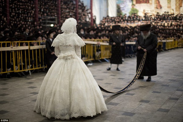 Rare occasion: Thousands of Hasidim Jews dressed in black watch as an Ultra Orthodox Jewish rabbi dances with the bride during the Mitvah tantz ritual 