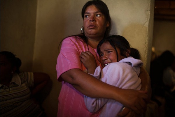 Một bé gái ôm người thân sau khi mẹ của cô bé bị giết trong một vụ đấu súng trên xe bus giữa các băng nhóm tội phạm.