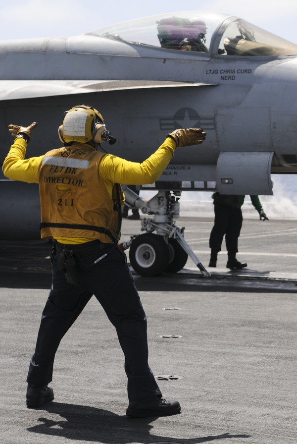 Một binh sĩ điều khiển một chiếc 'siêu ong bắp cày' F/A-18 vào vị trí để cất cánh từ tàu sân bay sân bay USS Nimitz.