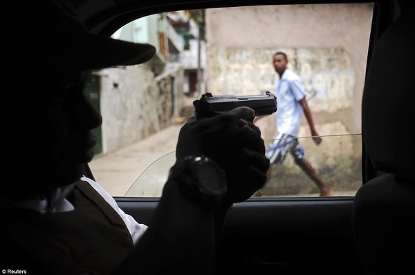 Cảnh sát chĩa súng vào một người qua đường, trong khi tuần tra tại khu ổ chuột Nordeste de Amaralina.