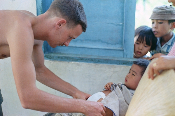 Nhân viên y tế của chương trình y tế dân sự (MEDCAP) đang chữa bệnh cho một em bé người Việt Nam.