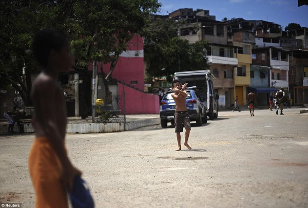 Một cậu bé làm ký hiệu hai khẩu súng khi đang chơi trên phố tại khu ổ chuột Nordeste de Amaralina.