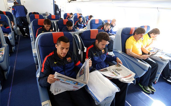 
	Các ngôi sao của Barca thoải mái đọc báo trên chuyến bay tới Munich