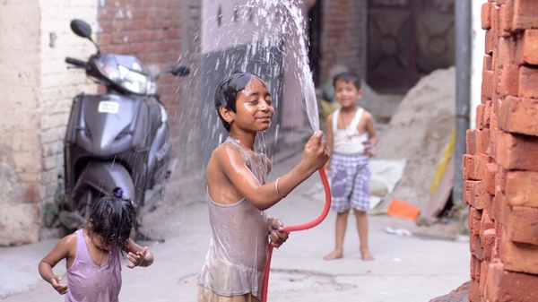 
	Một cậu bé Ấn Độ phun nước vào người để giải nóng
