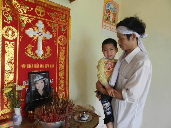 
	Anh Nguyễn Văn Vỹ (chồng nạn nhân) và con trai đau buồn trước bàn thờ của chị Huyên