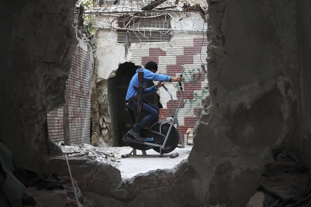 Chiến binh phiến quân tập thể dục trên xe đạp tại chỗ trong ngôi nhà đổ nát ở thành phố Aleppo, Syria.