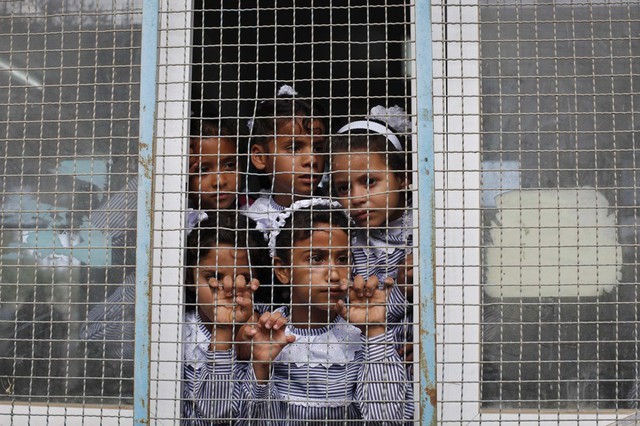 Trẻ em người Palestin nhìn ra ngoài cửa sổ lớp học của Liên Hợp Quốc ở Deir al-Balah, Dải Gaza.