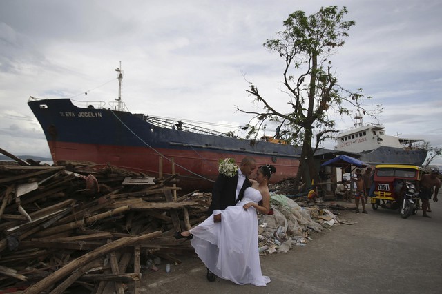 Một cặp đôi chụp ảnh cưới gần những ngôi nhà đổ nát và một tàu bị đánh dạt vào bờ sau siêu bão Haiyan ở Tacloban, Philippines.