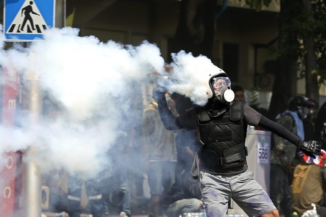 Một người biểu tình ném lựu đạn hơi cay trả lại cảnh sát trong cuộc đụng độ ở Bangkok, Thái Lan.