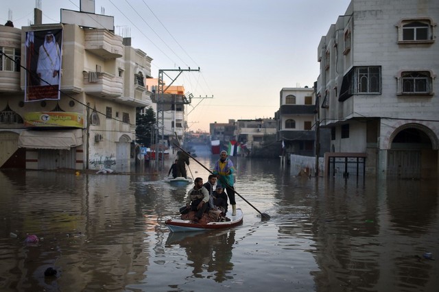 Người tình nguyện Palestine chèo thuyền trên đường phố ngập nước ở Dải Gaza.