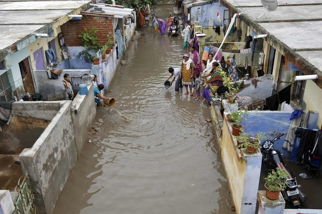 Mọi người cố gắng tát nước ra khỏi nhà ngập lụt ở Ahmedabad, Ấn Độ.